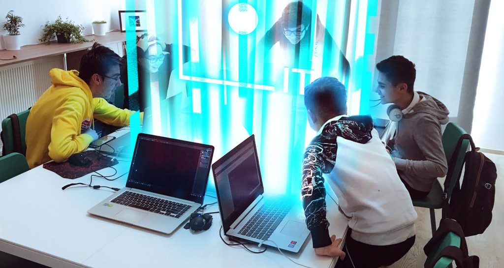 Copii lucrând la laptopuri în jurul unei mese